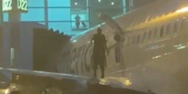 Yolcu acil çıkış kapısı ile uçaktan çıktı